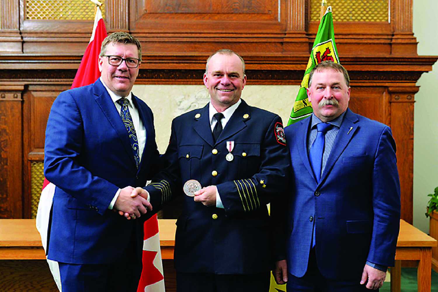 Saskatchewan Premier Scott Moe presenting a Premier�s Commendation Medallion to fire chief Brad Hutton with the Redvers Fire Department. At right is Cannington MLA Daryl Harrison.